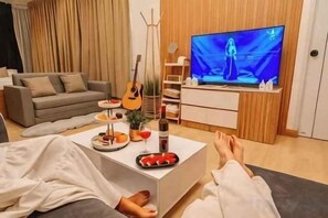 Un salon avec une télévision, un canapé, une table basse et une guitare.