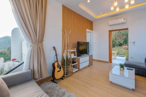 A modern living room with a sofa, a coffee table, a TV, and a guitar.
