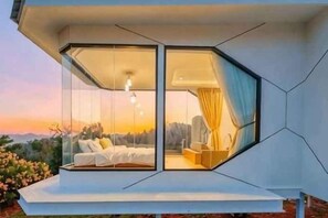 Une chambre à coucher moderne avec un mur en verre, un lit et une table de chevet.