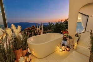 A freestanding bathtub in a modern bathroom with a view of the mountains.