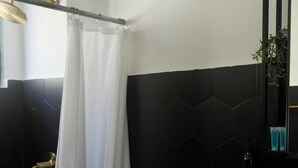 Ein Badezimmer mit Toilette, Waschbecken, Dusche und schwarzen, sechseckigen Fliesen.