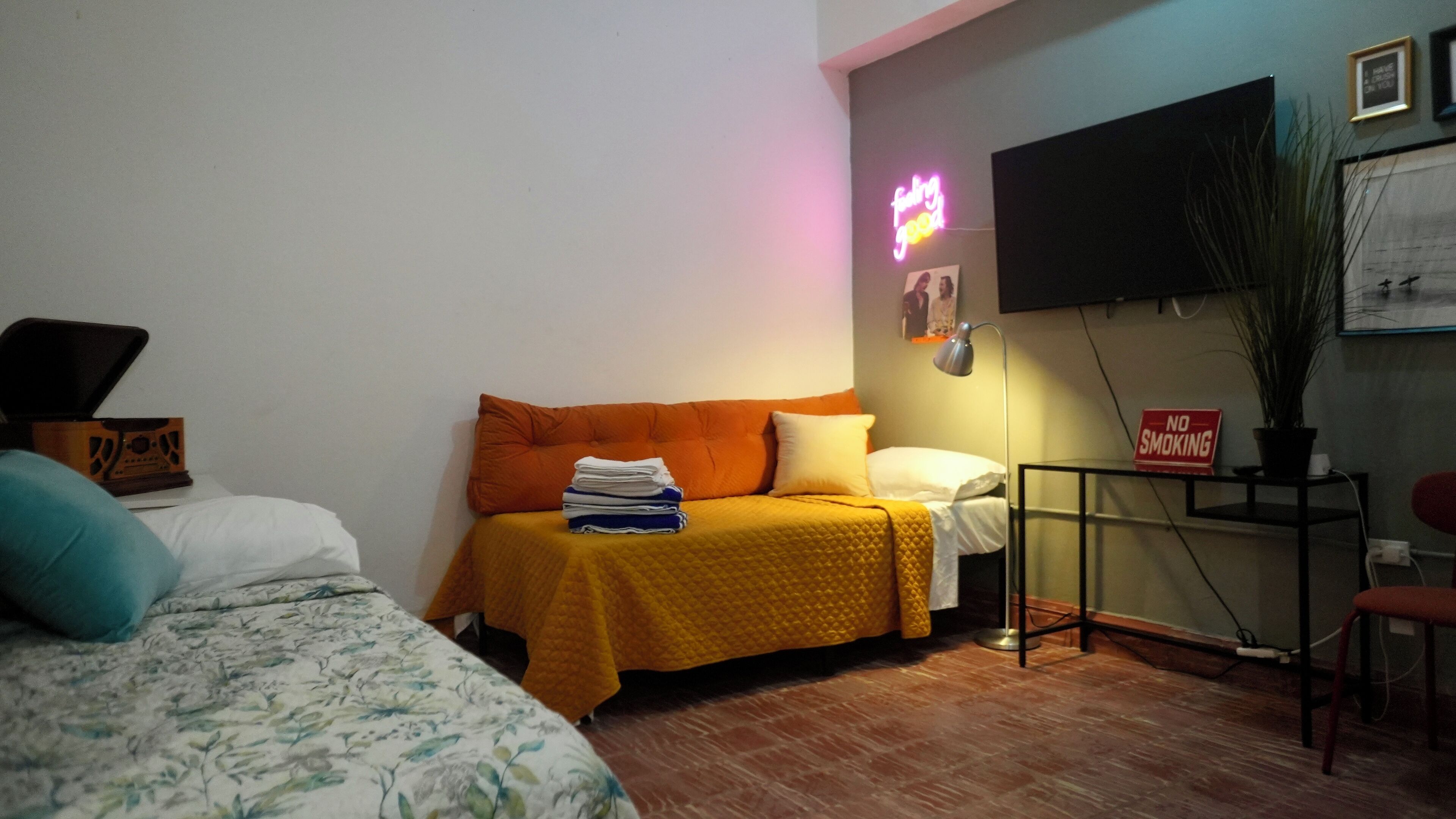 A bedroom with a bed, a sofa, a desk, and a TV.