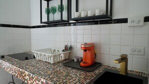 Eine Küche mit gefliestem Fliesenspiegel, einer Kaffeemaschine, einem Spülbecken und einer Arbeitsplatte mit Korb und Geschirr.