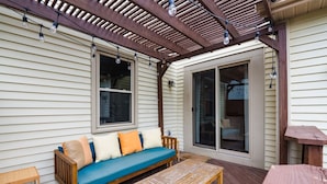 Une terrasse couverte avec un banc en bois, une table et un canapé agrémenté de coussins.