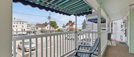 Un balcon donnant sur une rue, avec une table et deux chaises.
