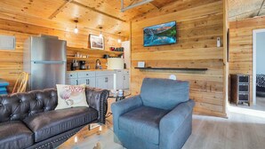 Un intérieur en bois avec un canapé, un fauteuil et un coin cuisine.