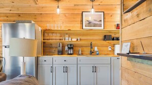 Une cuisine moderne avec des murs en bois, un réfrigérateur en acier inoxydable, une machine à café et un évier.