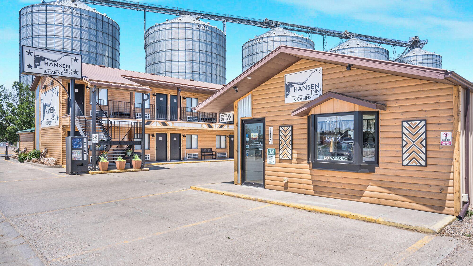 A Hansen Inn & Cabins with a motel office, wooden cabins, and grain silos in the background.