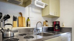 A kitchen with stainless steel appliances, a kettle, a coffee maker, and various utensils on the counter.