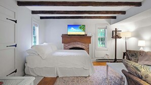 A bedroom with a bed, a fireplace, a television, and a sofa.