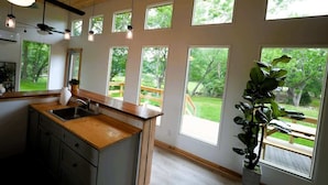 Une cuisine moderne dotée de grandes fenêtres, de plans de travail en bois et offrant une vue sur l’extérieur.