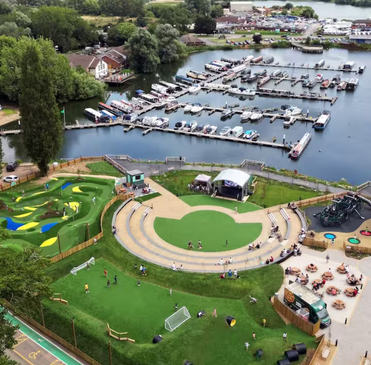 Een jachthaven met aangemeerde boten, een speeltuin voor kinderen en een sportveld.