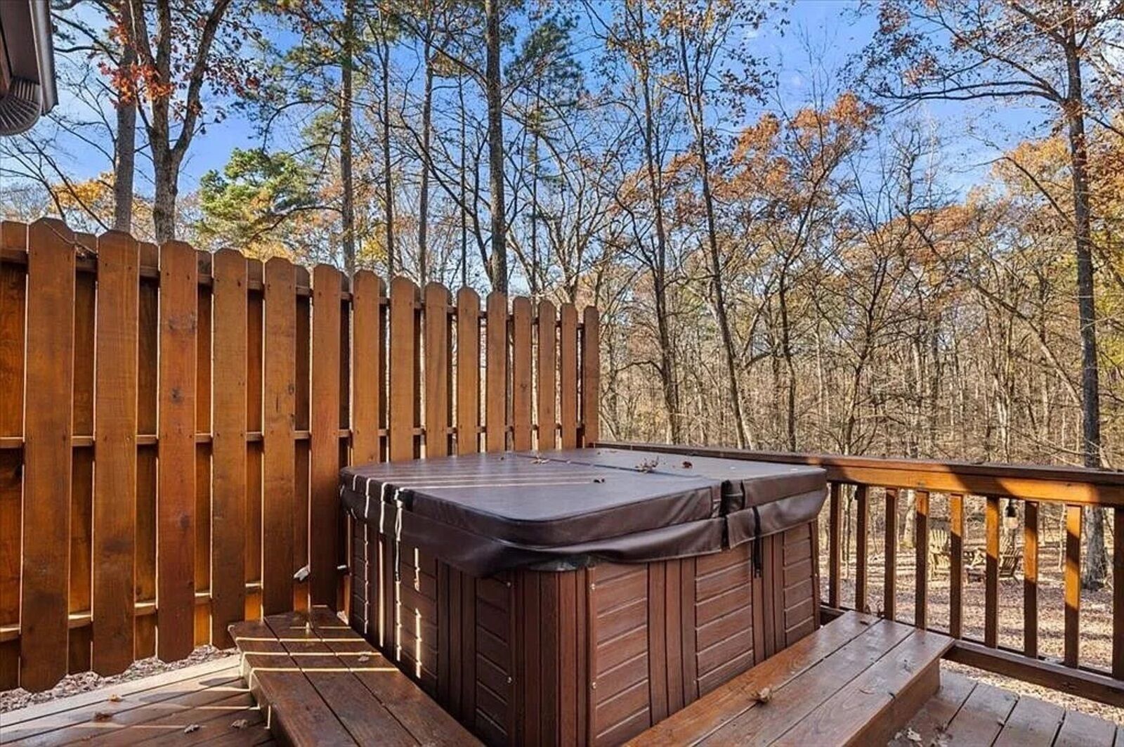 A wooden deck with a hot tub and a wooden fence.