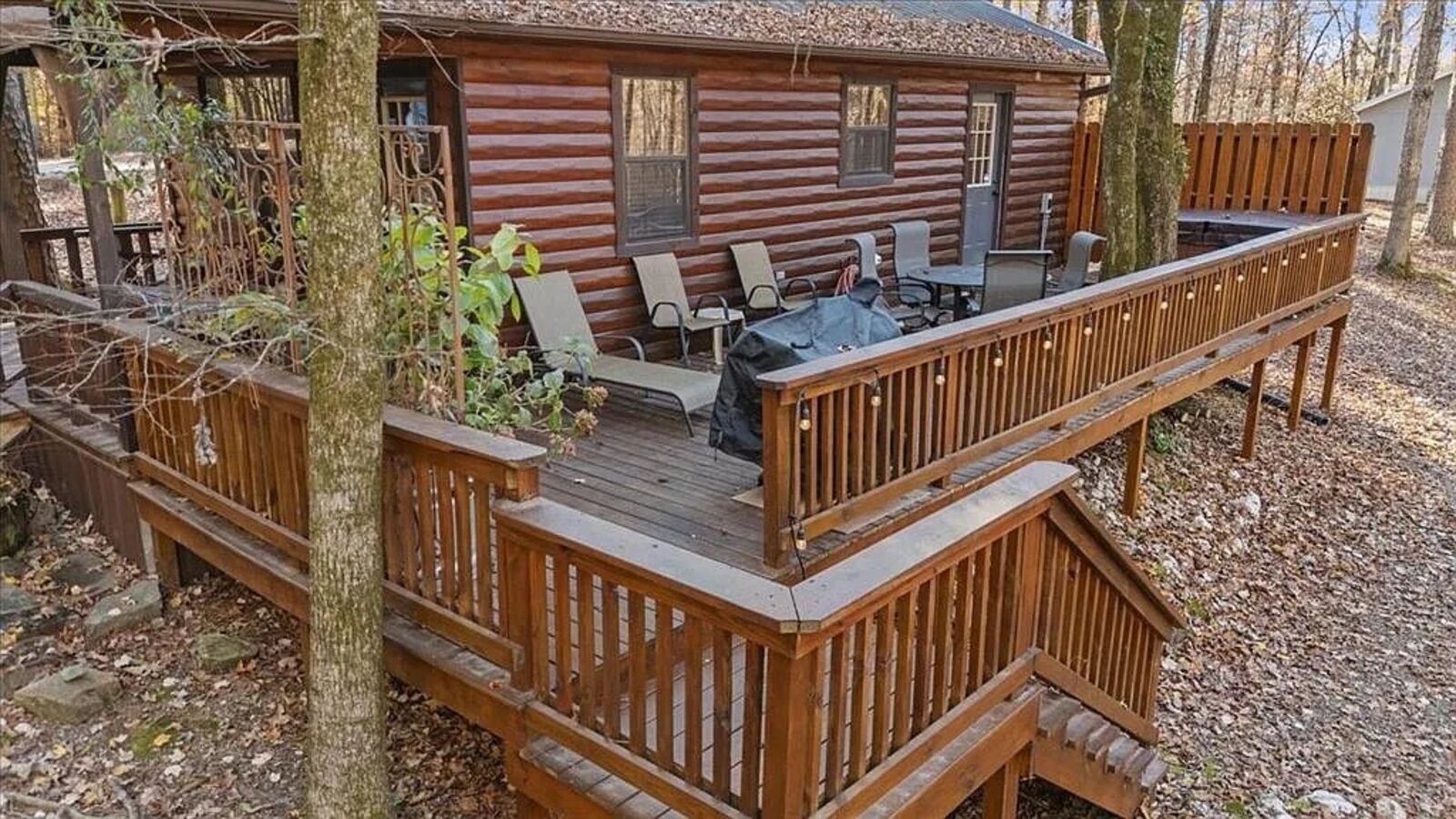 Eine Blockhütte mit einer Terrasse, Sitzgelegenheiten im Freien und einem Grillplatz.