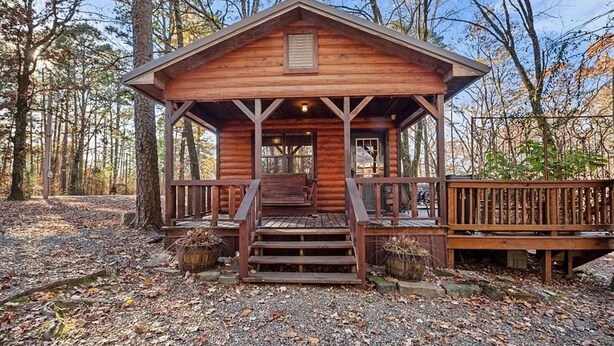 A wooden cabin with a porch and steps leading to the entrance. - Rustic Retreat W/ Hot Tub • Firepit - BBQ (Broken Bow)