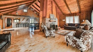 Een ruime loft met hoge plafonds, houten balken, een open haard, een eetgedeelte en een woonkamer met lederen meubels.