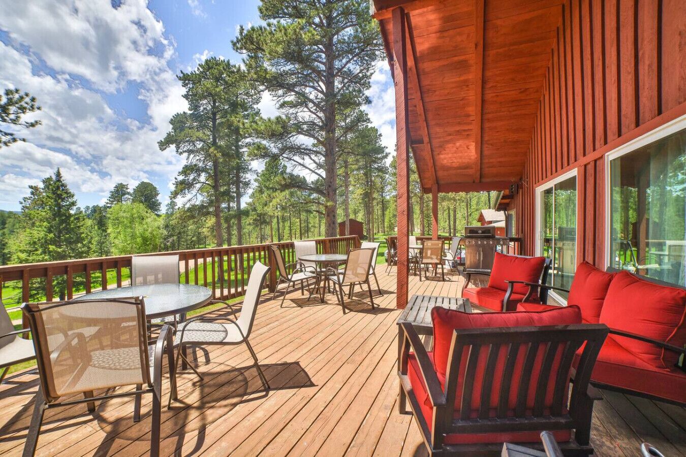 Une terrasse en bois, aménagée avec du mobilier d’extérieur, notamment des chaises et une table, donnant sur une zone boisée.