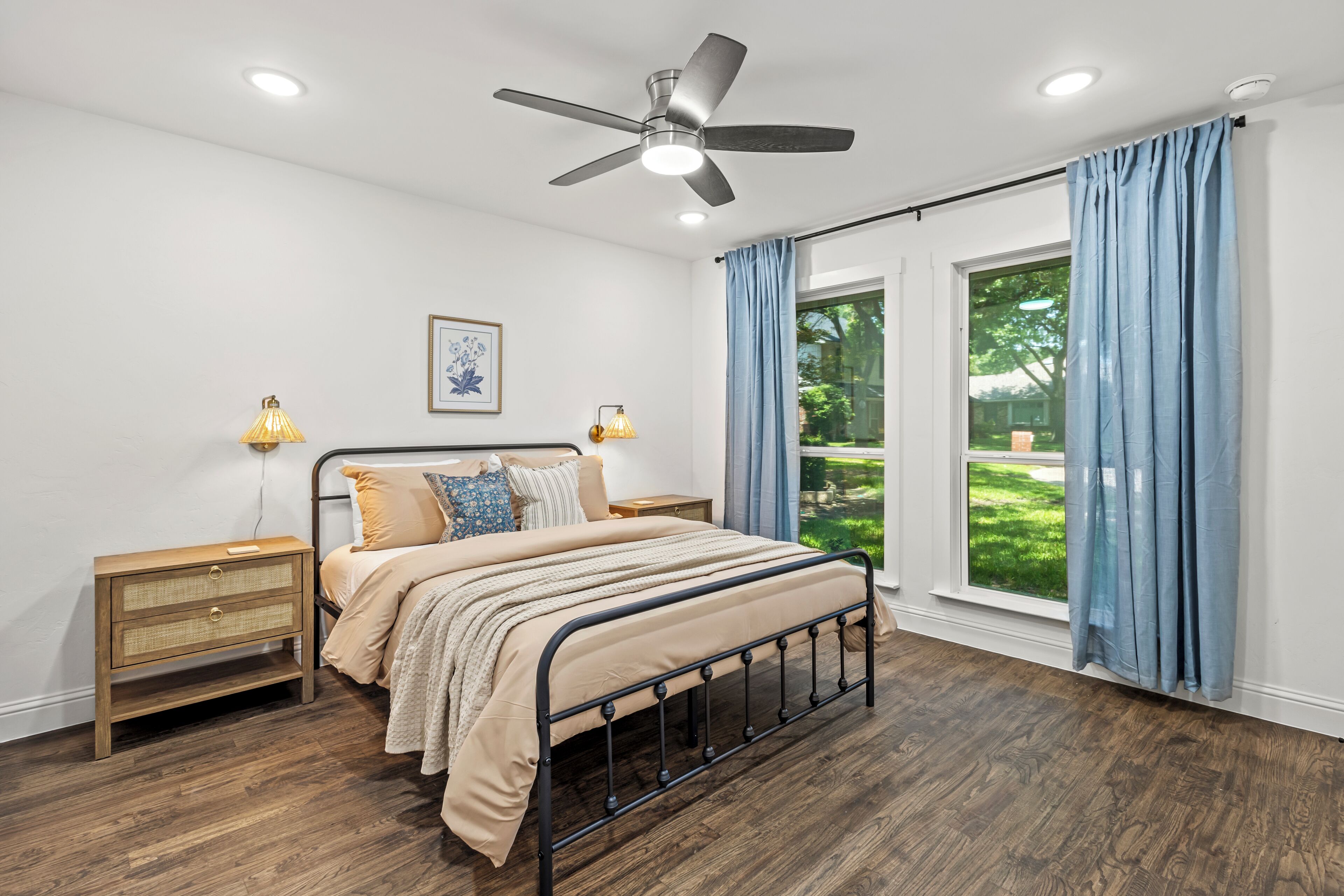 A bedroom with a bed, bedside tables, a ceiling fan, and a window with curtains.