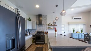 A modern kitchen with a large island, stainless steel appliances, and pendant lighting. - Stunning Ocean View Home on Nature Reserve (Esterillos Este)