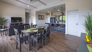 A modern kitchen with a central island, bar stools, and a dining area with a table and chairs. - Stunning Ocean View Home on Nature Reserve (Esterillos Este)