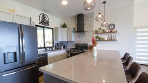 A modern kitchen with a large island, stainless steel appliances, and pendant lighting. - Stunning Ocean View Home on Nature Reserve (Esterillos Este)