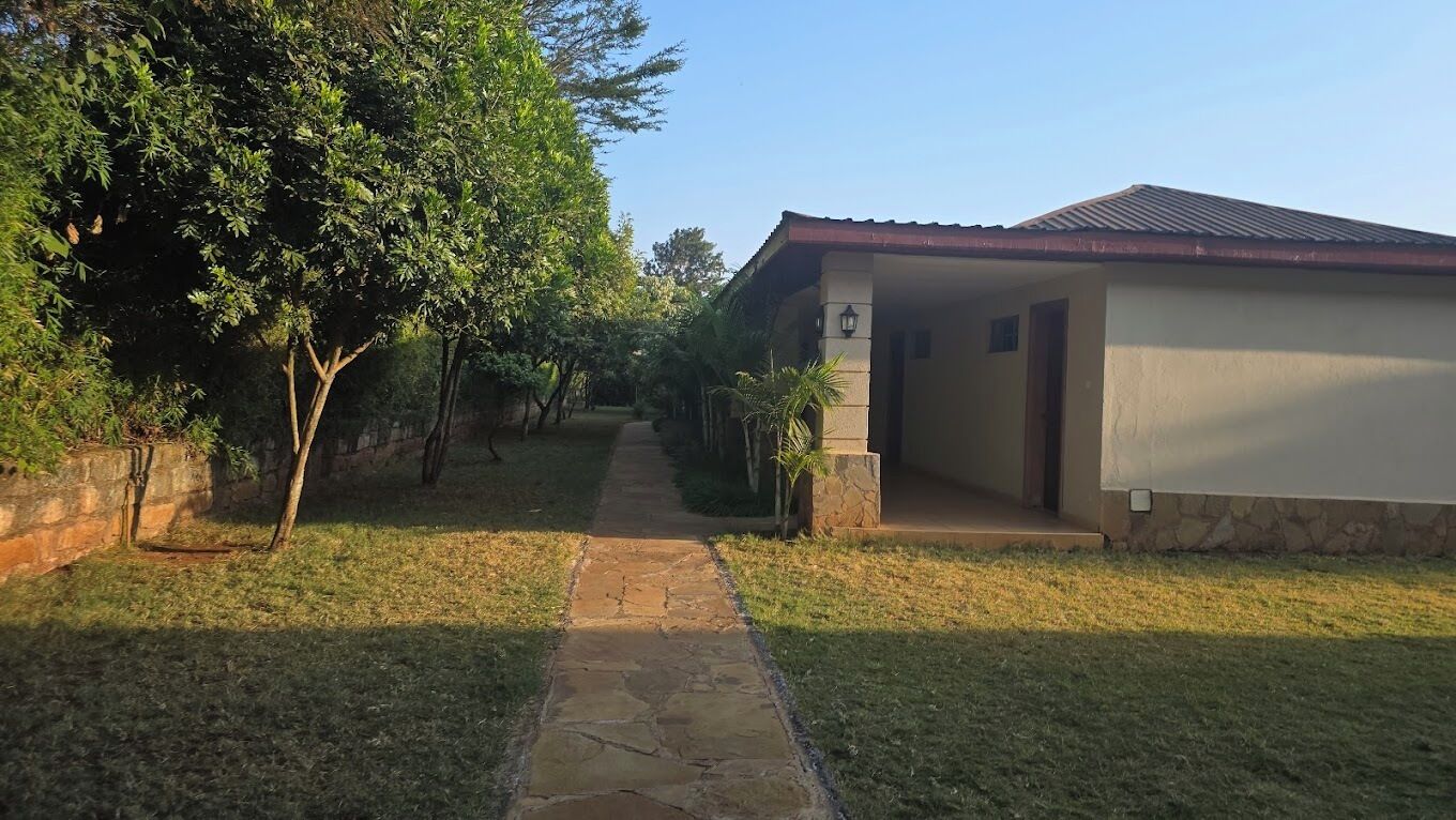 A pathway leading to a building with a tiled roof and a stone base.