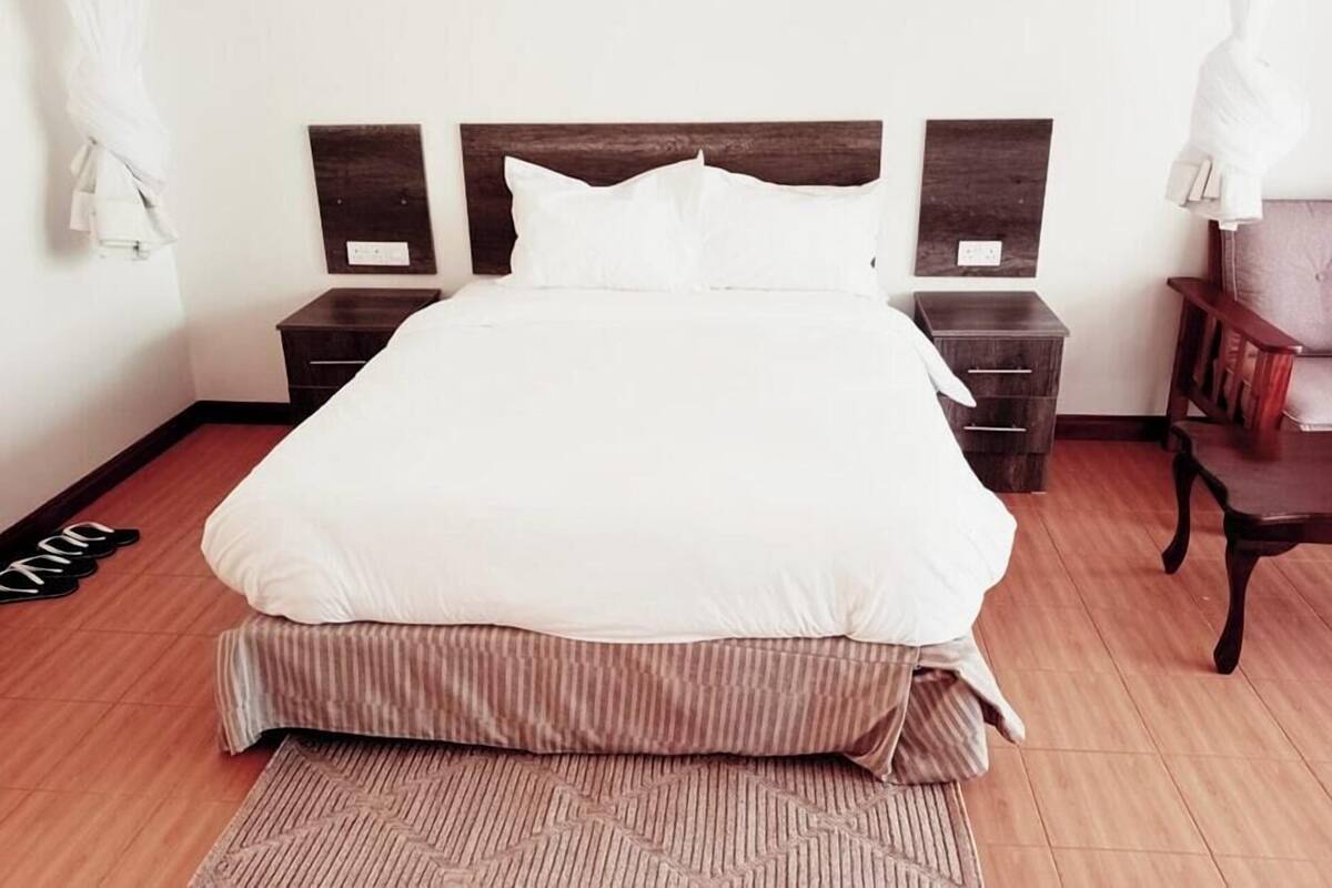 A neatly made bed with a wooden headboard, two bedside tables, and a wooden floor.
