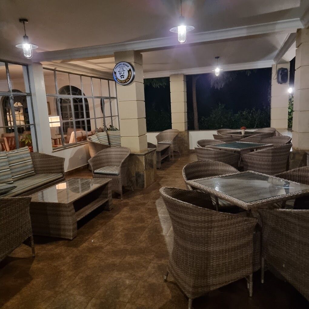Un espacio al aire libre con mobiliario de mimbre y mesas de vidrio, con vistas al cielo nocturno.