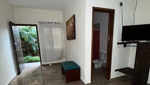 Amplia sala de estar con piso de baldosas, un banco, un cuadro y un televisor.