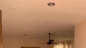 Una habitación con dos camas, ventilador de techo, un cuadro y una lámpara.