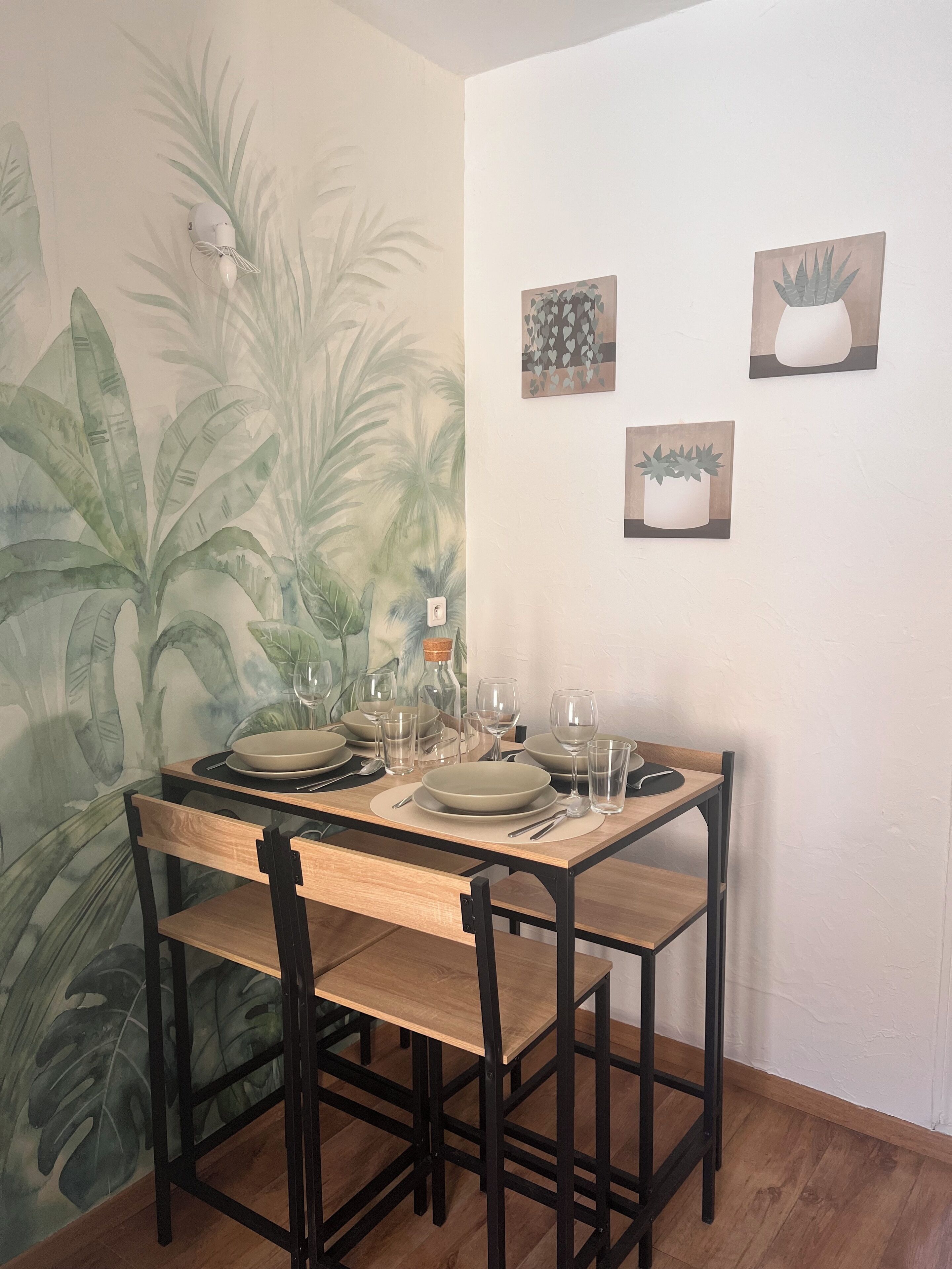 A dining area with a table set for four, chairs, and wall art.