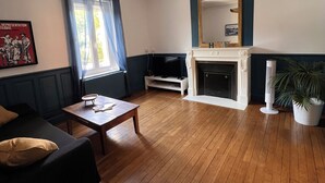 A living room with a fireplace, a ceiling fan, and a large mirror. - Apartment in the heart of Le Creusot (Le Creusot)
