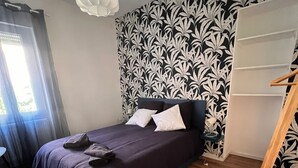 A bedroom with a bed, a wooden ladder, a patterned wallpaper, and a ceiling light. - Apartment in the heart of Le Creusot (Le Creusot)