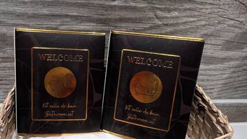 Deux panneaux d’accueil noirs, avec des lettres dorées et un emblème circulaire, disposés dans un panier tressé.