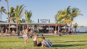An outdoor seating area with umbrellas, palm trees, and a sign for 'OYSTER SHED.'