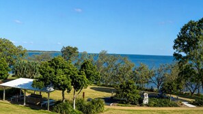 A coastal view with a covered picnic area, trees, and a clear sky.