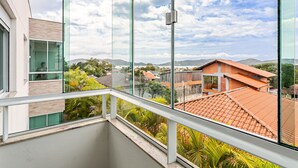Ein Balkon mit Blick auf eine Wohngegend, darunter Häuser mit roten Ziegeldächern und viel Grün.
