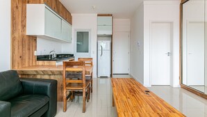 Eine moderne Küche mit Holzschränken, ein Essbereich mit Holztisch und -stühlen sowie eine schwarze Ledersofa.