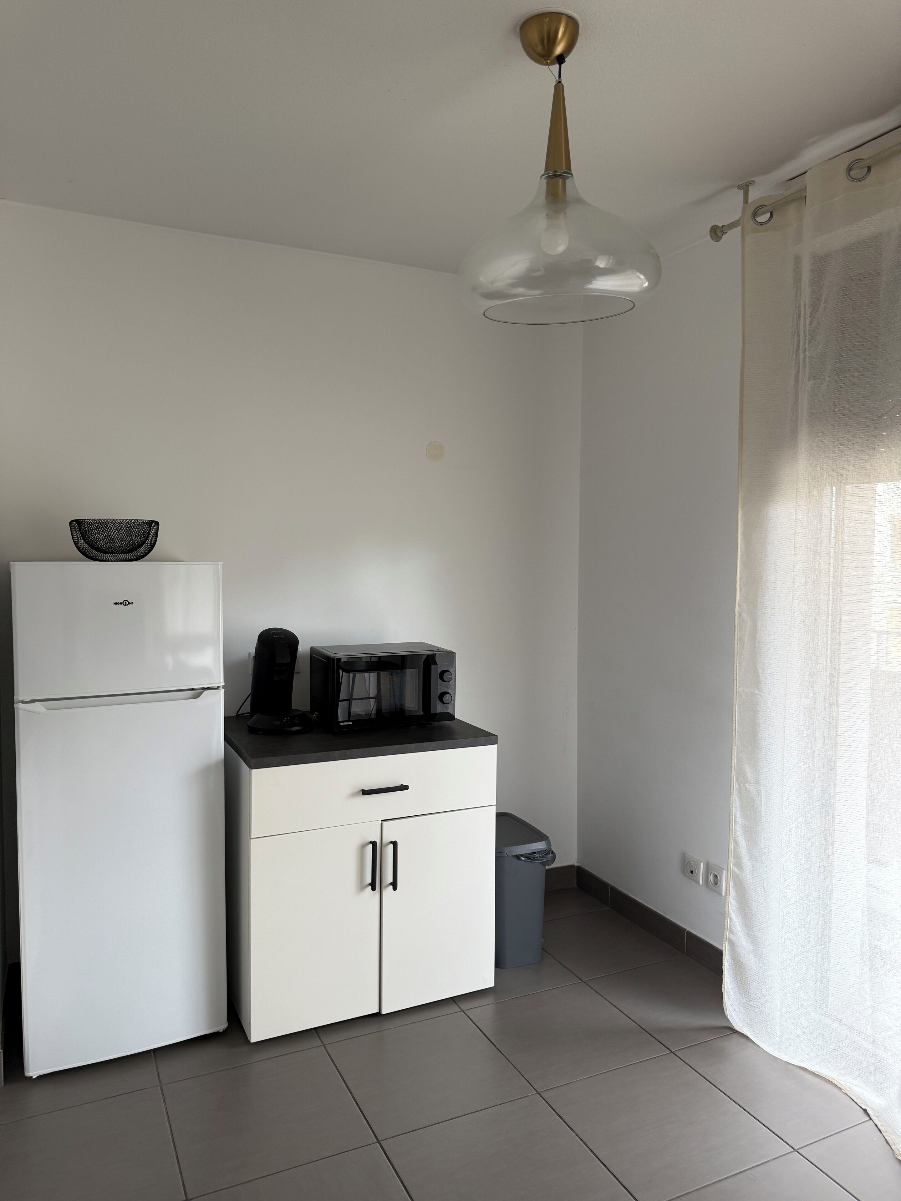 Une petite cuisine équipée d’un réfrigérateur, d’un four à micro-ondes et d’un petit placard.