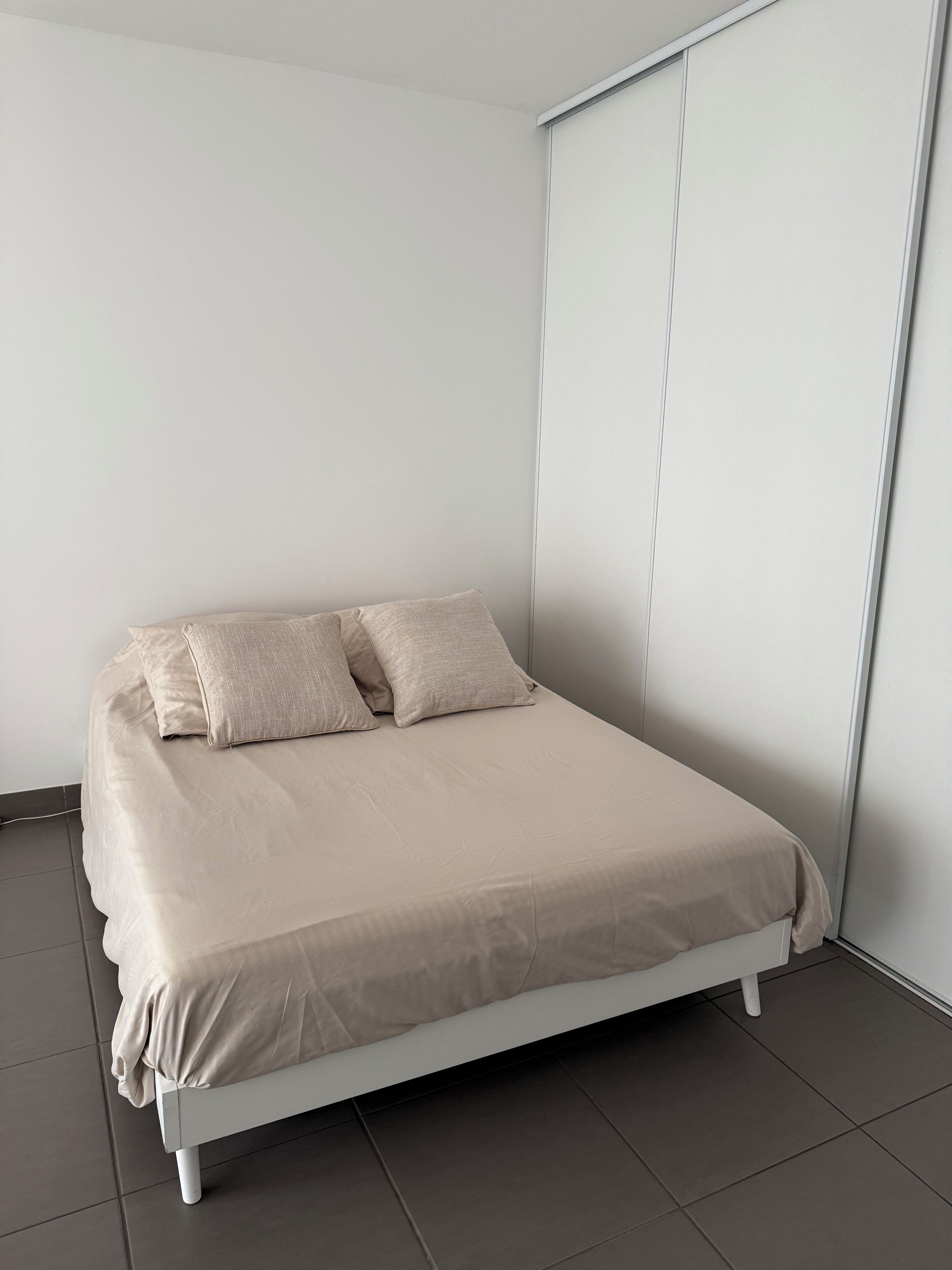Une chambre à coucher au style minimaliste, avec un lit, des murs blancs et une porte coulissante.