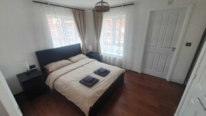 Un dormitorio con una cama, dos mesitas de noche y una puerta.