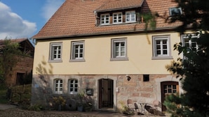 A two-story building with a tiled roof, stone foundation, and multiple windows. - Idyllic vacation home in the countryside in the Rhön (Oberthulba)