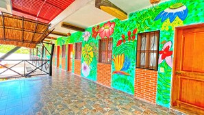 A covered outdoor area with tiled flooring, wooden doors, and colorful murals on the walls. - Hotel Mayas Blue (Bacalar)