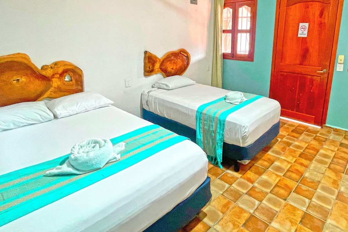 A hotel room with two beds, each with wooden headboards and white bedding.