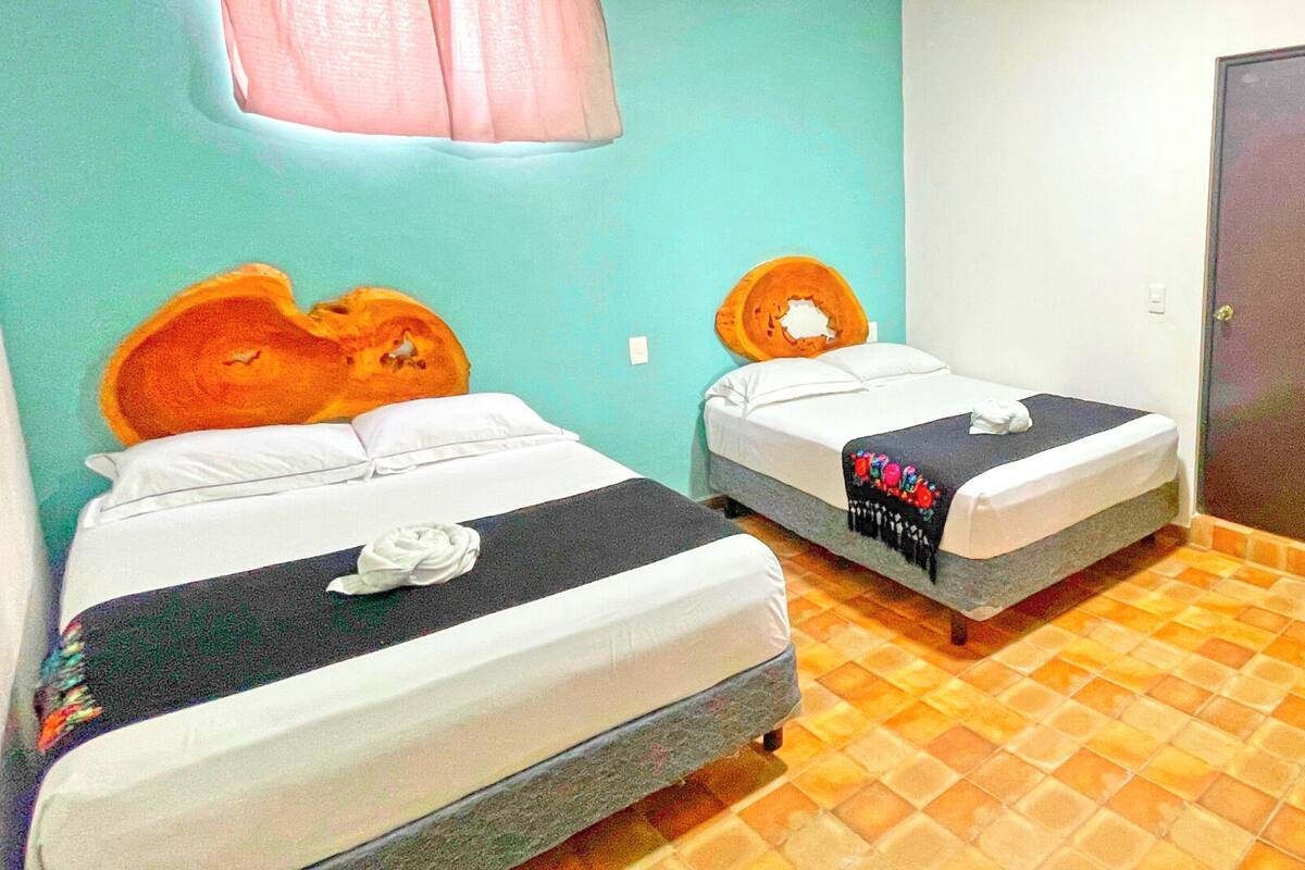 Two single beds with white linens and a black blanket, a wooden headboard, and a tiled floor.