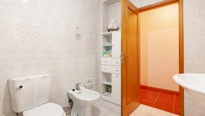 A bathroom with a toilet, bidet, and a wooden door leading to another room. - A place to rest (Gualtar)