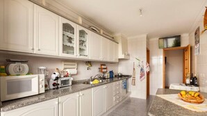 A kitchen with white cabinets, a granite countertop, a microwave, a toaster, and a sink. - A place to rest (Gualtar)