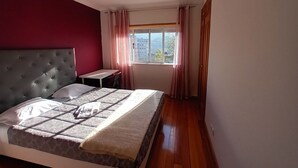 A bedroom with a bed, a desk, and a window with curtains. - A place to rest (Gualtar)