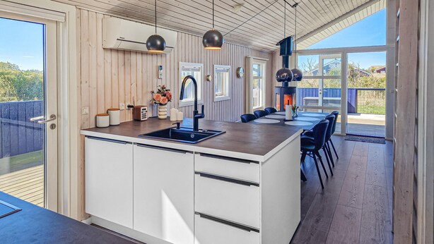 A modern kitchen with a central island, white cabinetry, and a built-in stove.