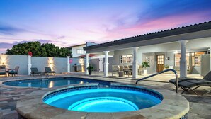 Une piscine avec un jacuzzi, un espace salon extérieur et un patio couvert.
